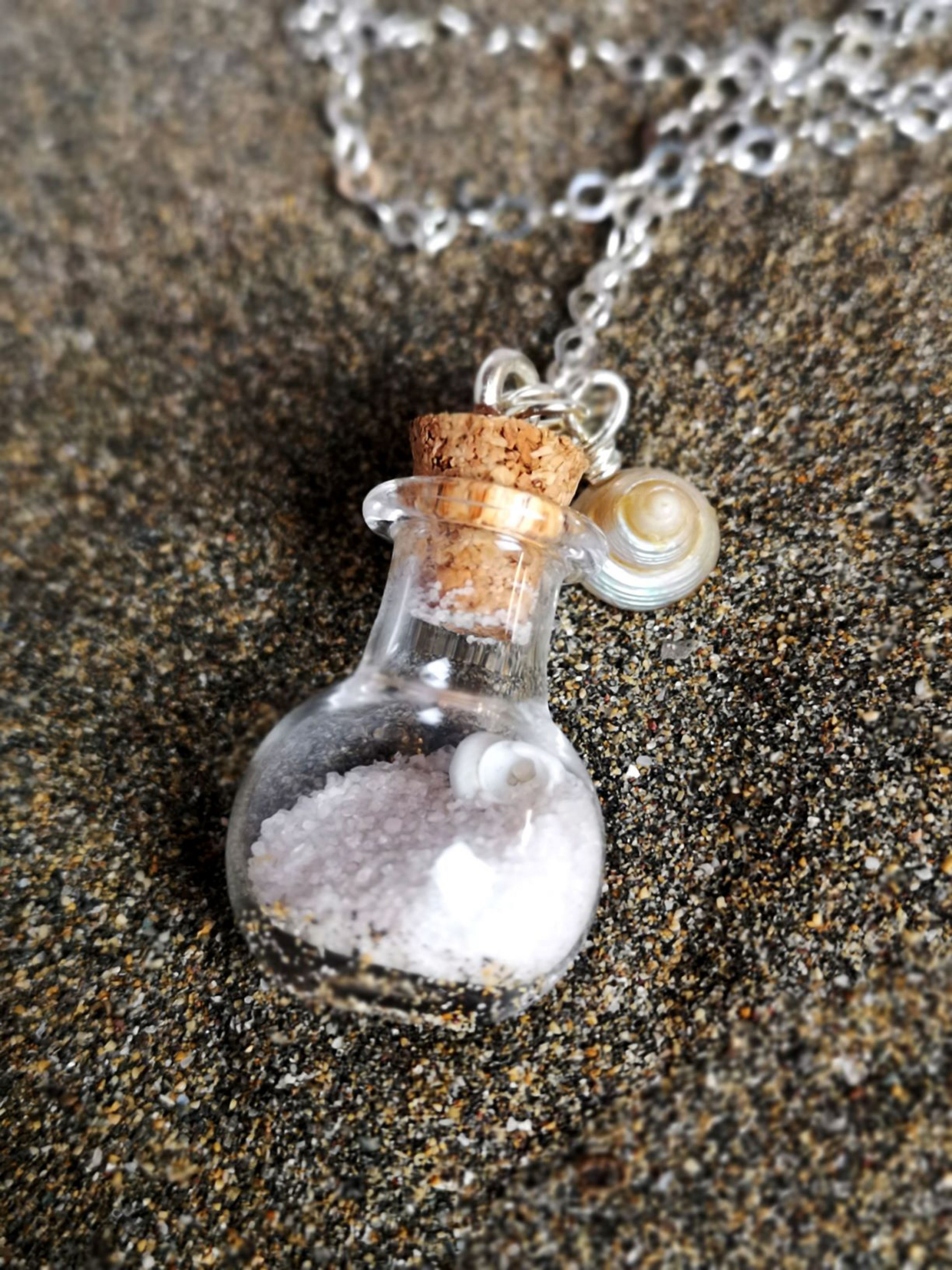 Glasflasche mit Muscheln und Sand